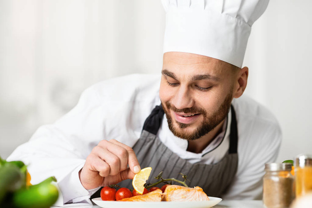 Chef profesional Chef Plating Salmón plato de pie en la cocina del restaurante
 - Foto, Imagen