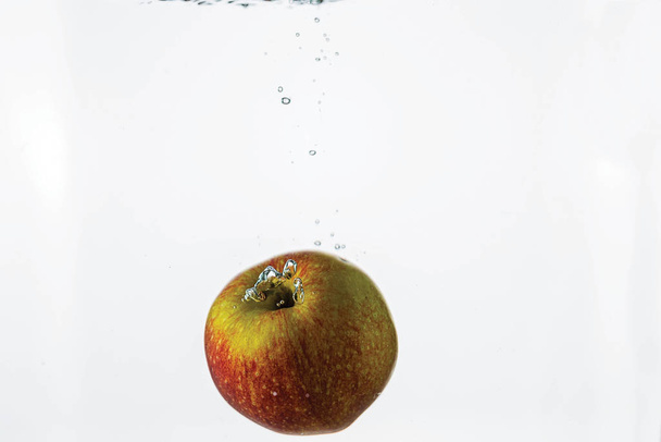 Close up view splashing water and red apple on white background. Beautiful backgrounds. - Foto, afbeelding