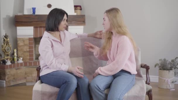 Side view of brunette Caucasian woman listening carefully to her adult daughter talking emotionally. Teen daughter sharing problems with mother at home. Trust, reliance, family relationship. - Materiaali, video