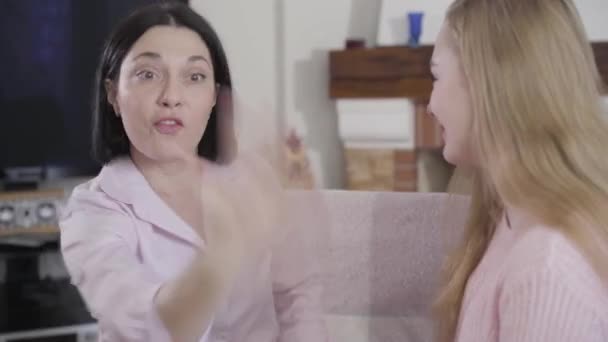 Close-up of young brunette Caucasian woman talking emotionally to blond girl. Mother spending free time with daughter at home. Trust, reliance, family relationship. - Felvétel, videó