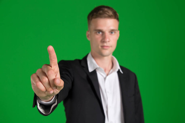 Young man indicates something, finger closeup, blurred face, isolated on green background. Press the virtual button with your finger. - Fotoğraf, Görsel