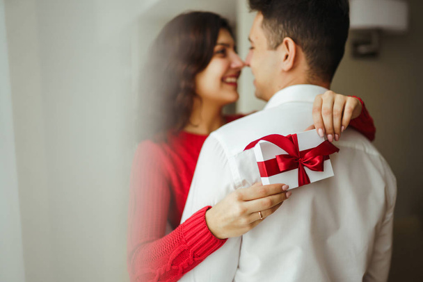 Happy couple with gift hugging. Cheerful couple with gift in hands enjoying each other. Valentines day celebration concept. Relationship, surprise and love concept. - Photo, image
