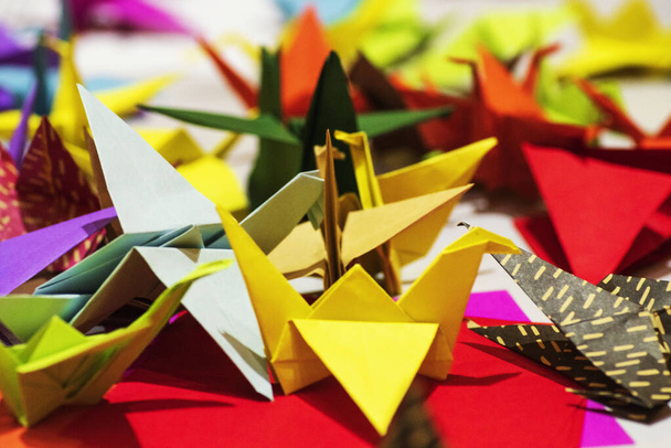 Kolor żurawie papierowe origami z papieru.Multi-kolorowe origami w postaci żurawi na stole. Symbol Origami. - Zdjęcie, obraz