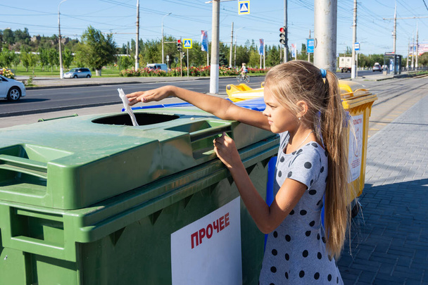 Το κορίτσι πετάει μια πετσέτα στα σκουπίδια. - Φωτογραφία, εικόνα