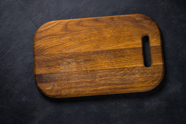 Black wooden cutting board on black table. - Photo, Image
