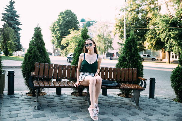 A girl in a black shirt and shorts in a park on a bench - 写真・画像