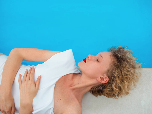 krásná zrzka (zázvor) kudrnatá žena v bílém plavkách ležící u bazénu v letním dni. Léto, štěstí, relax, wellness, rekreační koncept - Fotografie, Obrázek
