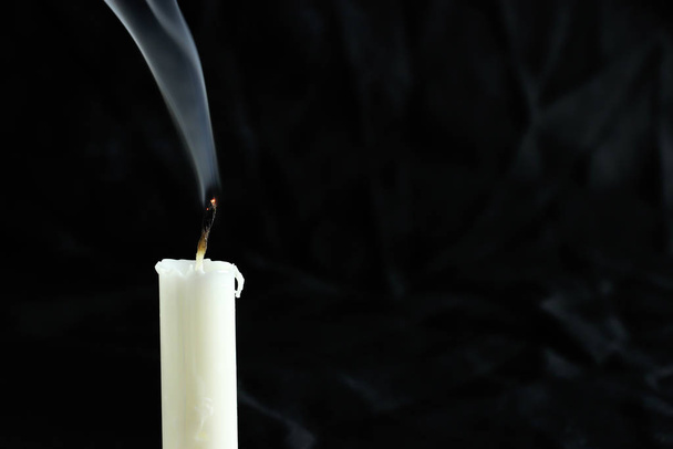 An extinct candle with smoke on a black background. copy space for your text - Photo, image