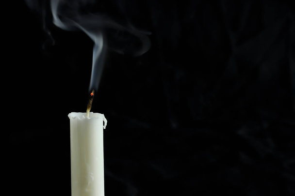 Una vela extinta con humo sobre un fondo negro. copiar espacio para su texto
 - Foto, imagen