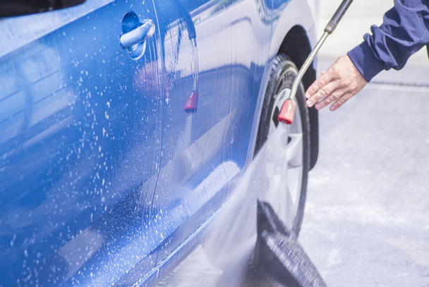 Manual car wash with pressurized water in car wash outside.Cleaning Car Using High Pressure Water. - 写真・画像
