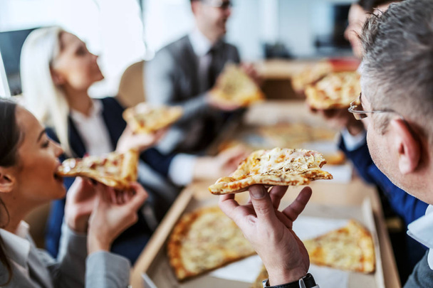 Ebédszünetet tartó fehérgalléros munkások csoportja.Éhesek és élvezik a pizzát.. - Fotó, kép