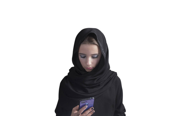 Siyah abaya giymiş Arap bir kız ve elinde telefon olan beyaz bir geçmişi var. Müslüman Arap kız. - Fotoğraf, Görsel