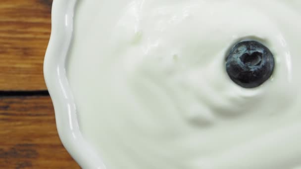 Rijp bosbessen die in natuurlijke yoghurt vallen - Video