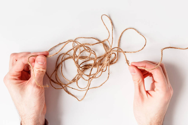 Man untangles a tangled thread. Top view isolated on a white background. - Foto, Imagen