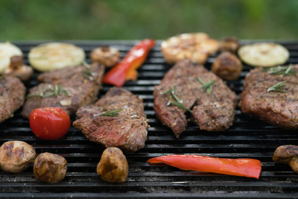Grilled beef steak on the grill with vegetables close-up. - Photo, Image