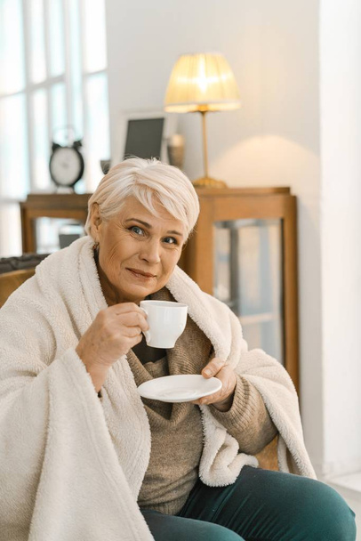 Cheerful Senior Woman Wrapped In A Warm Knitted Plaid Relaxing At Home - Fotó, kép