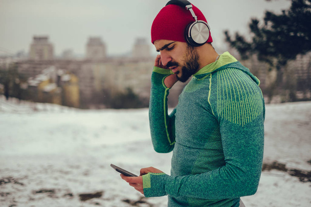 Baard atleet luisteren muziek buiten - Foto, afbeelding