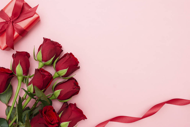 Valentine's Day, red roses and gift box with ribbon, over red background flat lay, birthday abstract background with copy space. - Foto, Imagem