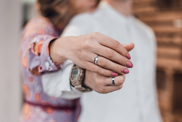 Романтическая пара, держащаяся за руки с обручальными кольцами
. - Фото, изображение
