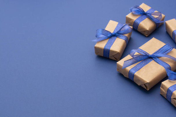 Christmas or birthday presents. Craft paper wrapped gift boxes on blue background, flat lay. Copy space. - Fotoğraf, Görsel