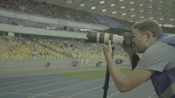 Un photographe photographes avec un appareil photo dans un stade pendant un match de football
. - Séquence, vidéo
