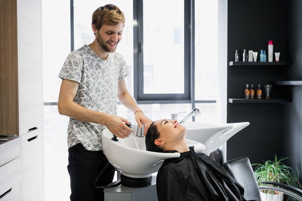 Frau bekommt Haarbehandlung in einem Wellness-Salon mit Shampoo für Haare, Schönheitssalon, Haarwäsche - Foto, Bild