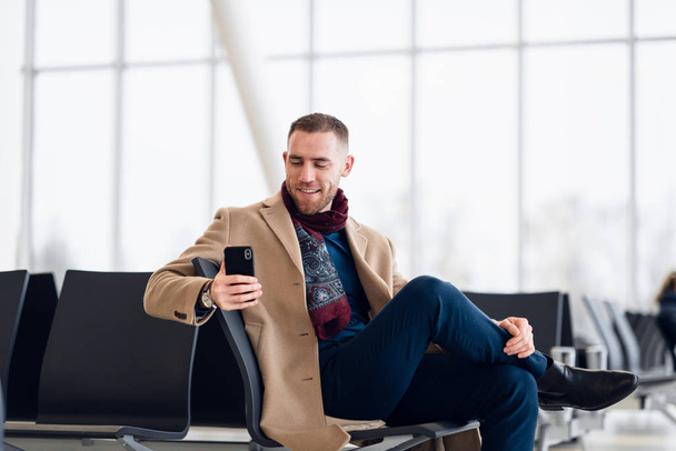 fiatal elfoglalt ember várakozás repülőtéren indulás a telefon használata közben - Fotó, kép