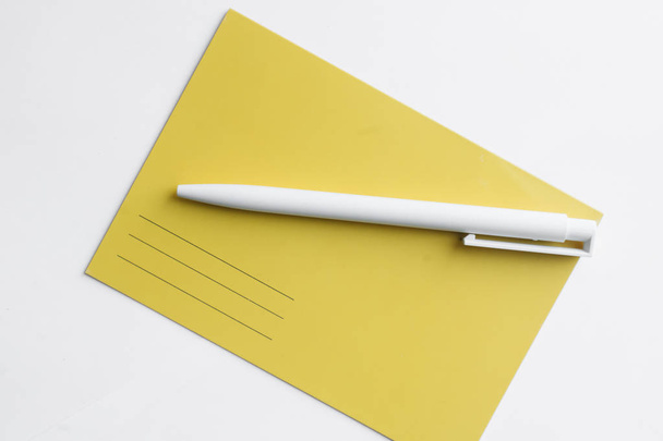 sárga képeslap és fehér hátterű toll, írjon egy listát - Fotó, kép