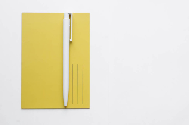 żółta kartka i długopis na białym tle, napisz listę - Zdjęcie, obraz