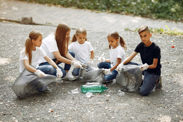 Children collects garbage in garbage bags in park - Fotografie, Obrázek
