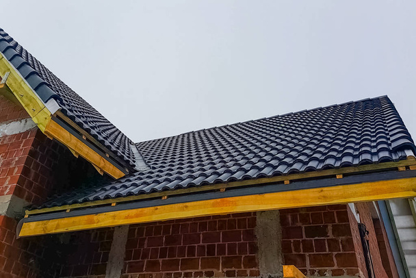 Εγκατάσταση της οροφής του σπιτιού από κεραμικά μαύρα πλακίδια. - Φωτογραφία, εικόνα