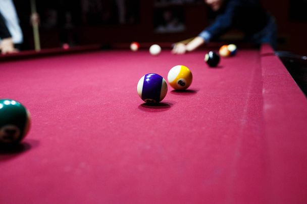 Boy plays billiard or pool in club. Young Kid learns to play snooker. Boy with billiard cue strikes the ball on table. Active Leisure, sport, hobby concept - Φωτογραφία, εικόνα