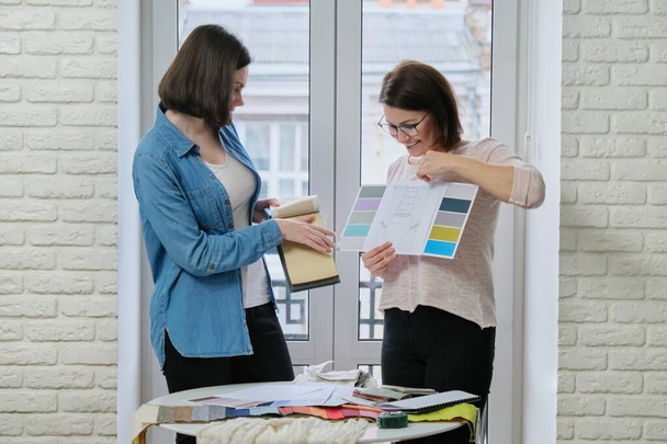 Females textile designer, decorator and client watch palettes with fabrics - Foto, afbeelding