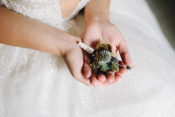 Close up of caucasian bride holding a delicate flower boutonniere on the day of her wedding  - Foto, Imagem