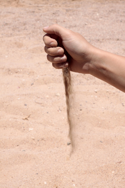 το γυναικείο χέρι χύνει έξω άμμο Ακρογιάλι - Φωτογραφία, εικόνα