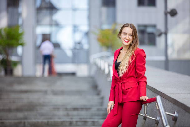 Attractive young woman standing on stairs in business district - Фото, изображение