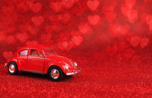 Red retro toy car on sparkling lights background. Valentines day. 8 March. Summer travel concept. Taxi. February 14 card. International Happy Women's Day. - Photo, Image