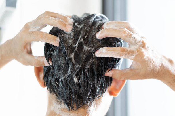 Крупним планом молодий чоловік миє волосся шампунем у ванній, вінтажний тон, вибірковий фокус
 - Фото, зображення