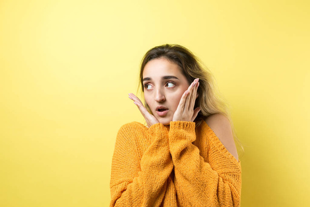 young woman with yellow hair and surprised face looking at camera isolated over beige background - Foto, afbeelding