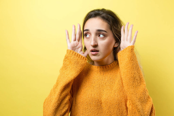 young beautiful woman with long hair in yellow sweater and green eyes looking at camera with fingers on head, - Photo, Image