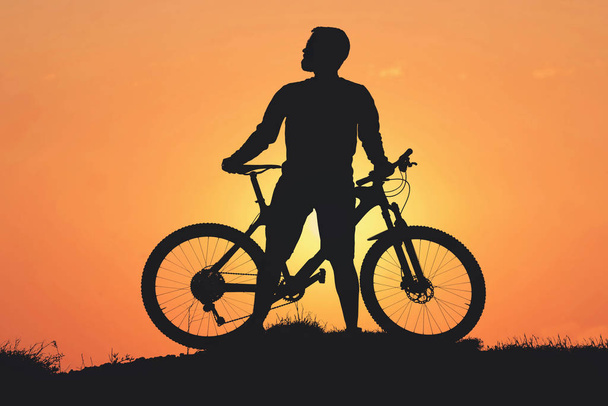 Conquistar picos de montaña por ciclista en pantalones cortos y jersey en una moderna bicicleta rígida de carbono con una horquilla de suspensión neumática. Hermosa vista desde la montaña. Vista panorámica de la pancarta. - Foto, Imagen