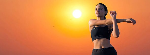 Egy vékony atlétikai lány szünetet tart az órák között a gyönyörű naplemente hátterében, élvezi a csendet és a szabadságot.. - Fotó, kép