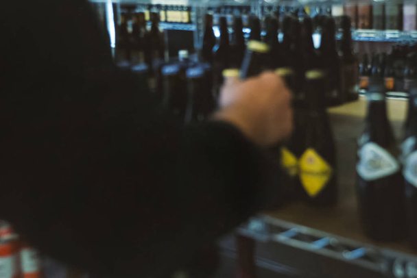 imagem turva, um borrão, o homem escolhe cerveja em uma loja no counte
 - Foto, Imagem