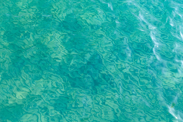 Textura de agua clara en azul. Fondo del océano y el mar retroiluminado por el sol
. - Foto, Imagen