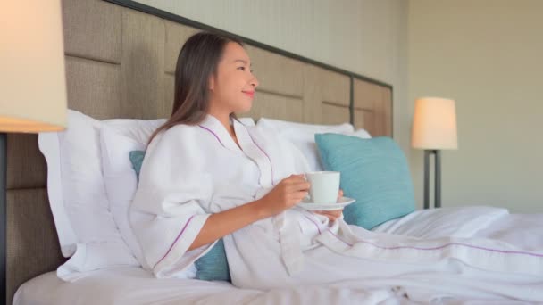 footage of beautiful asian woman drinking tea in bed at home - Filmagem, Vídeo