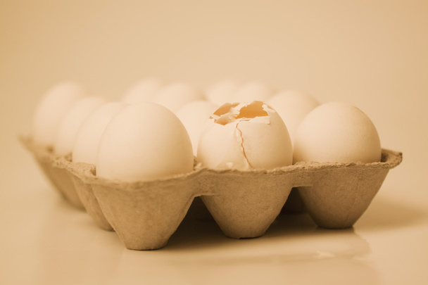 Broken egg in a carton with other eggs - Фото, изображение