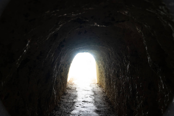 Wyjście tunelowe z przelotem płynącym z ciemnoskalistej jaskini - Zdjęcie, obraz