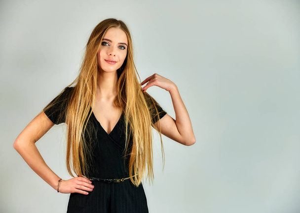 The concept of fashion and style. Portrait of a pretty blonde girl with long hair and great makeup on a white background. The model stands in different poses in front of the camera. - Zdjęcie, obraz