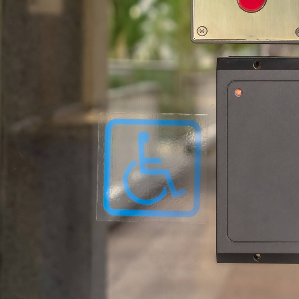 Cornice quadrata Porta in vetro di un edificio moderno con lettore di chiavi di sicurezza e segno di handicap
 - Foto, immagini