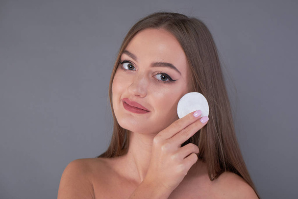 Healthy fresh girl removing makeup from her face with cotton pad. woman with a sponge wihte background cotton pad problem skin - Foto, immagini